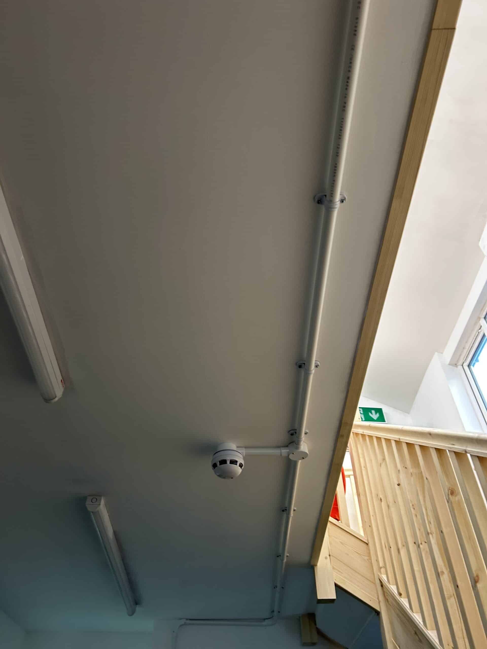 View of a ceiling with lights and fire alarm.